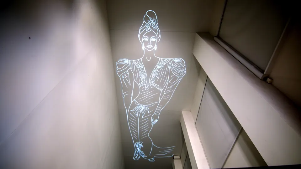 Eine leuchtende, minimalistische Linienzeichnung einer stilisierten Frau in eleganter Kleidung wird an die Decke eines modernen, schmalen Raumes projiziert.